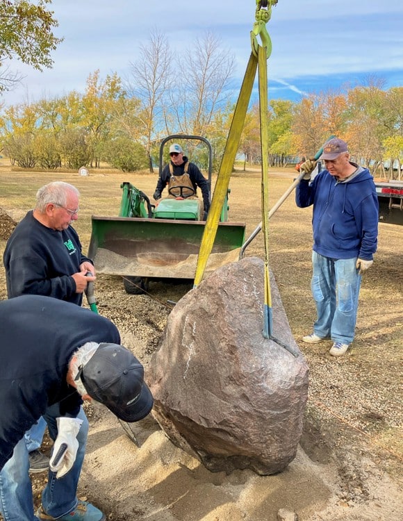 Heavy machinery and lifting straps in action as rocks are moved.